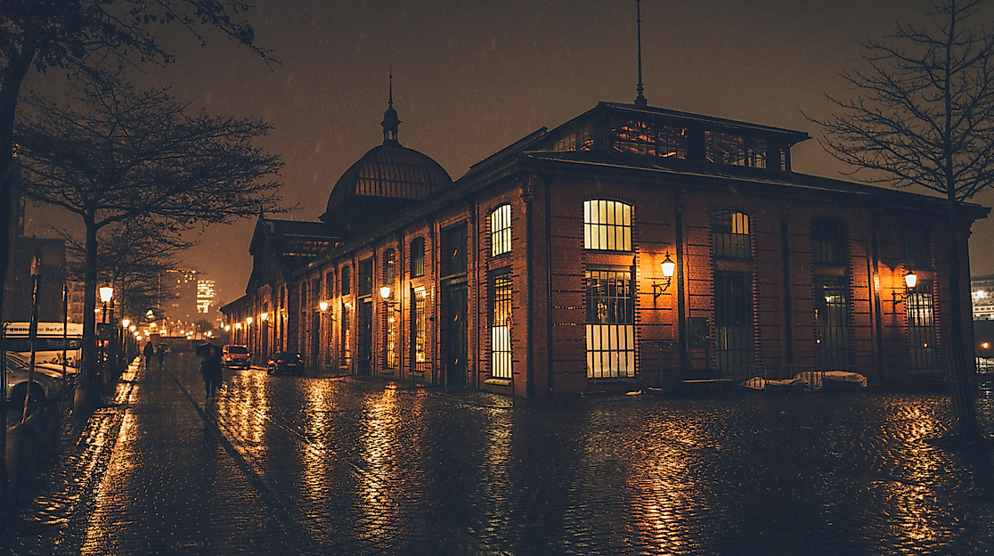 Fischauktionshalle in Hamburg festively lit at night with reflections on the wet ground